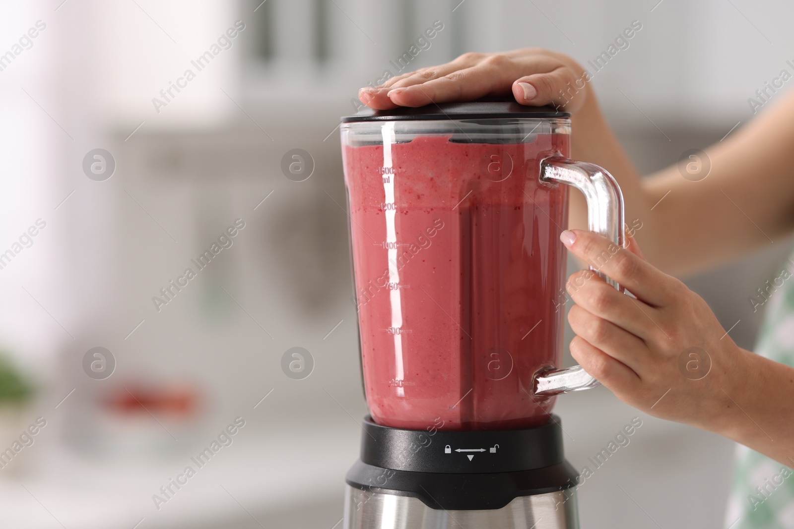 Photo of Woman making delicious smoothie with blender in kitchen, closeup. Space for text