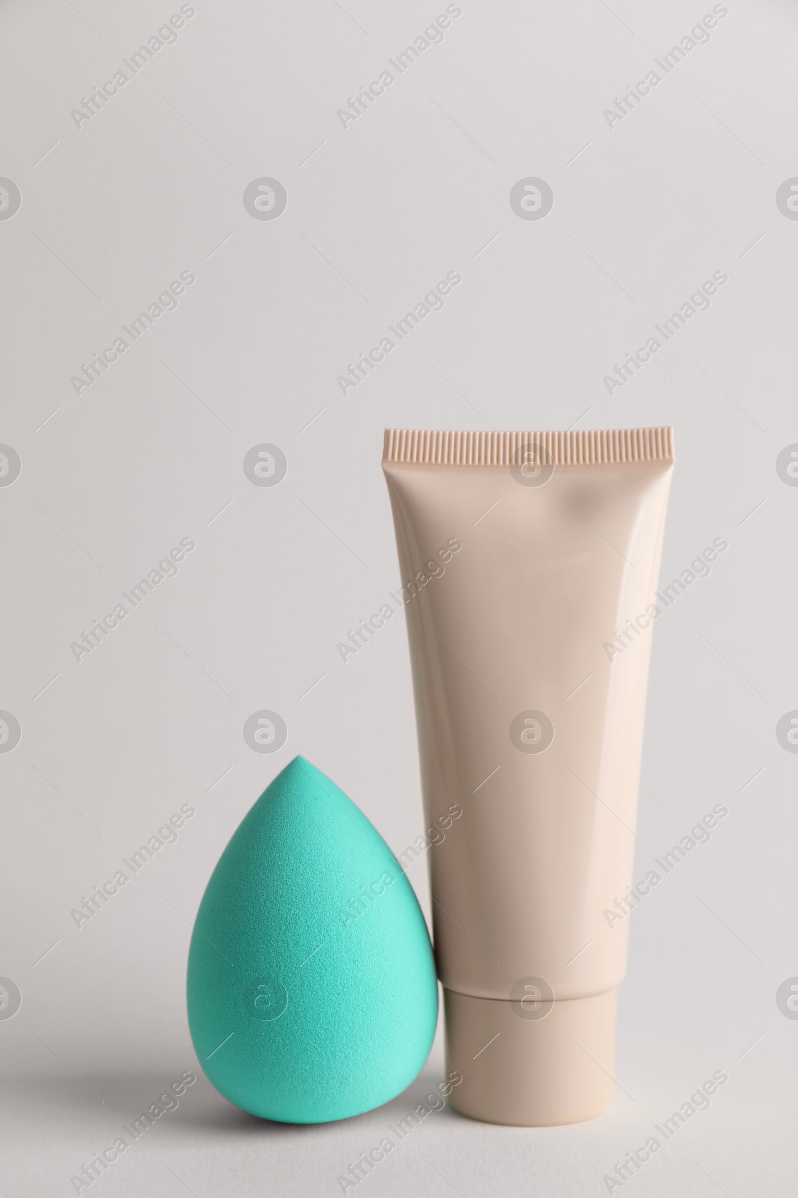 Photo of Makeup sponge and skin foundation on light grey background