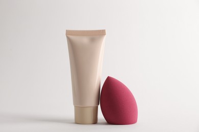 Photo of Makeup sponge and skin foundation on light grey background