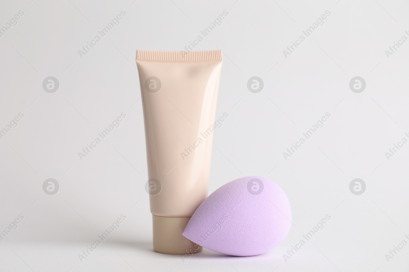 Photo of Makeup sponge and skin foundation on light grey background