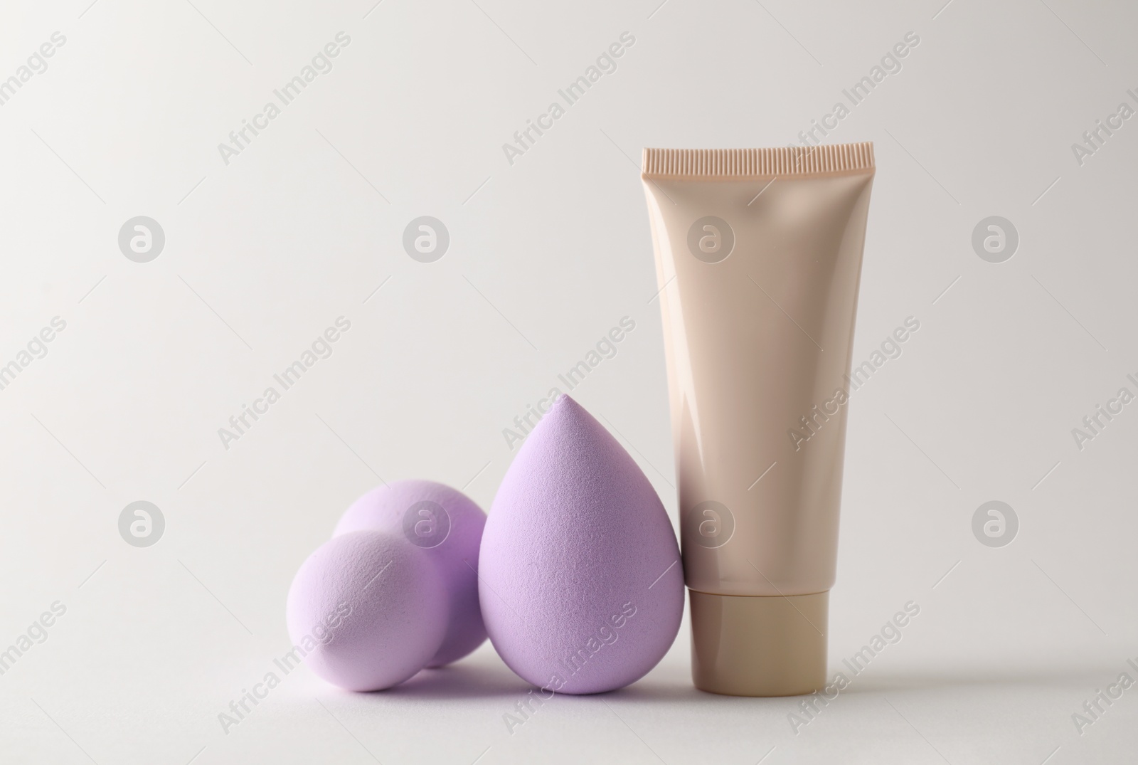 Photo of Makeup sponges and skin foundation on light grey background