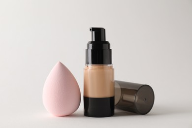 Photo of Makeup sponge and skin foundation on light grey background