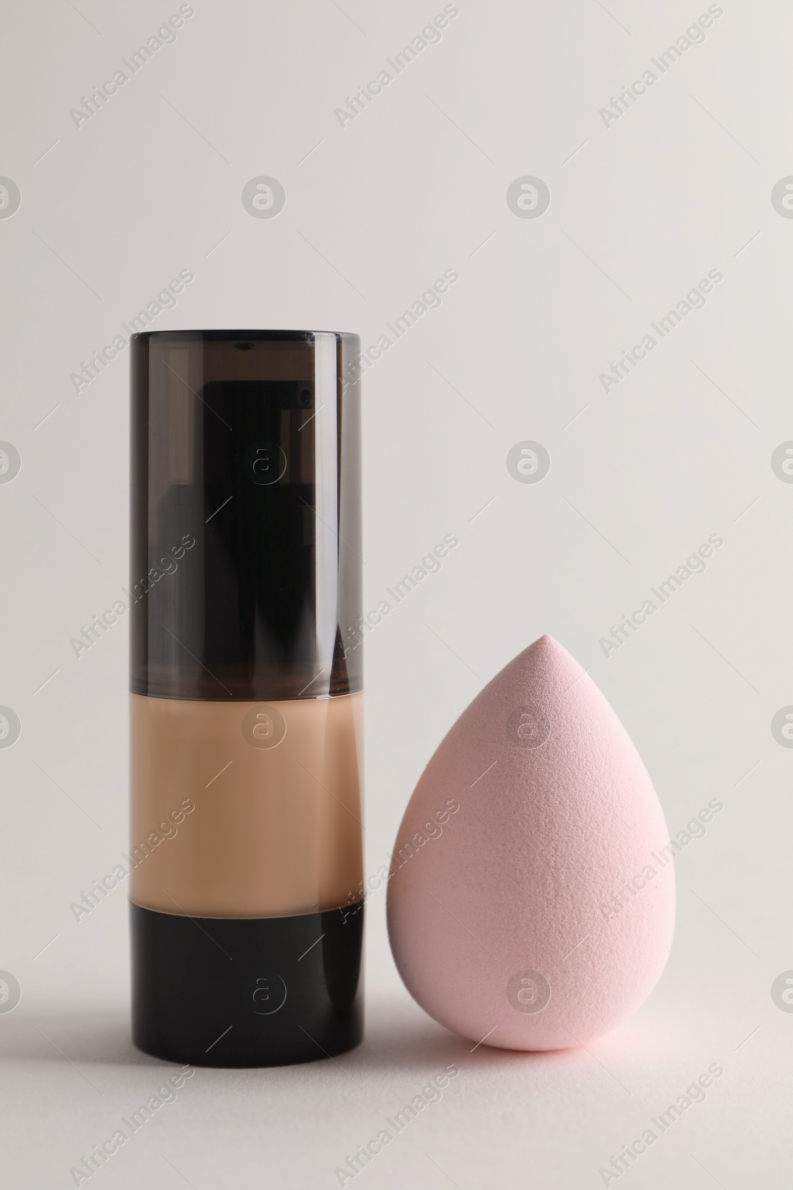 Photo of Makeup sponge and skin foundation on light grey background