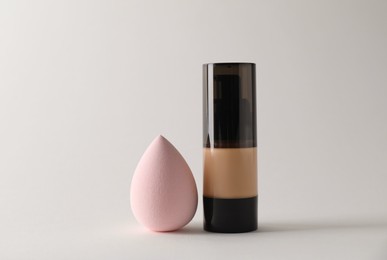 Photo of Makeup sponge and skin foundation on light grey background