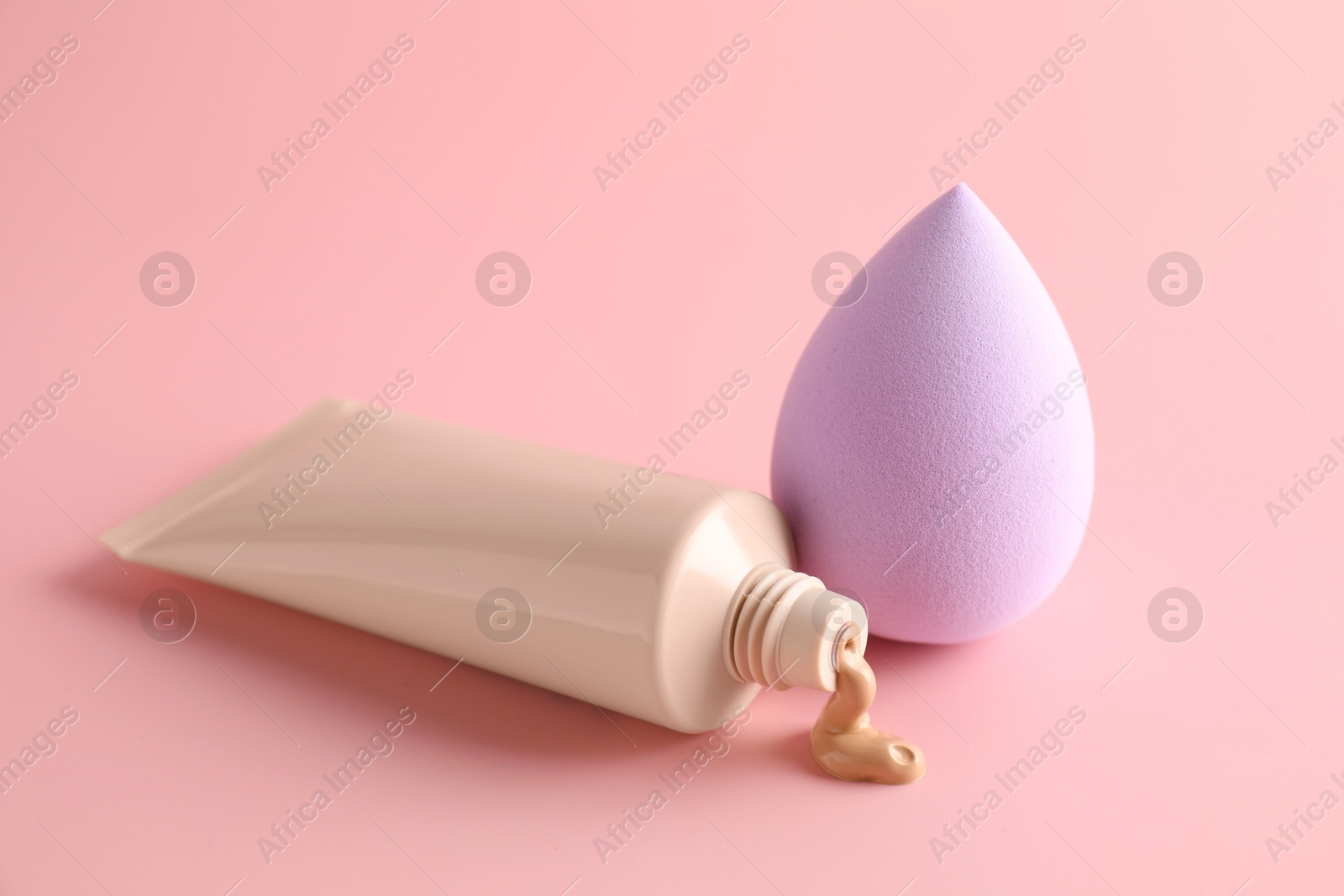 Photo of Makeup sponge and skin foundation on pink background