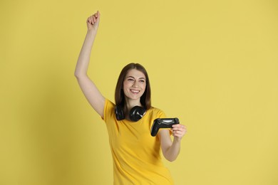 Photo of Happy woman playing video games with controller on yellow background