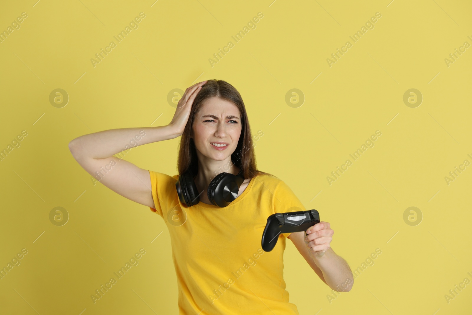 Photo of Unhappy woman with controller on yellow background