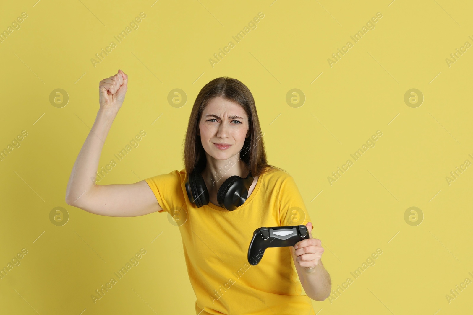 Photo of Woman playing video games with controller on yellow background