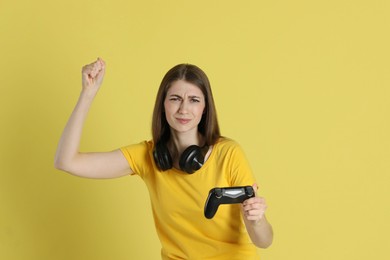 Woman playing video games with controller on yellow background