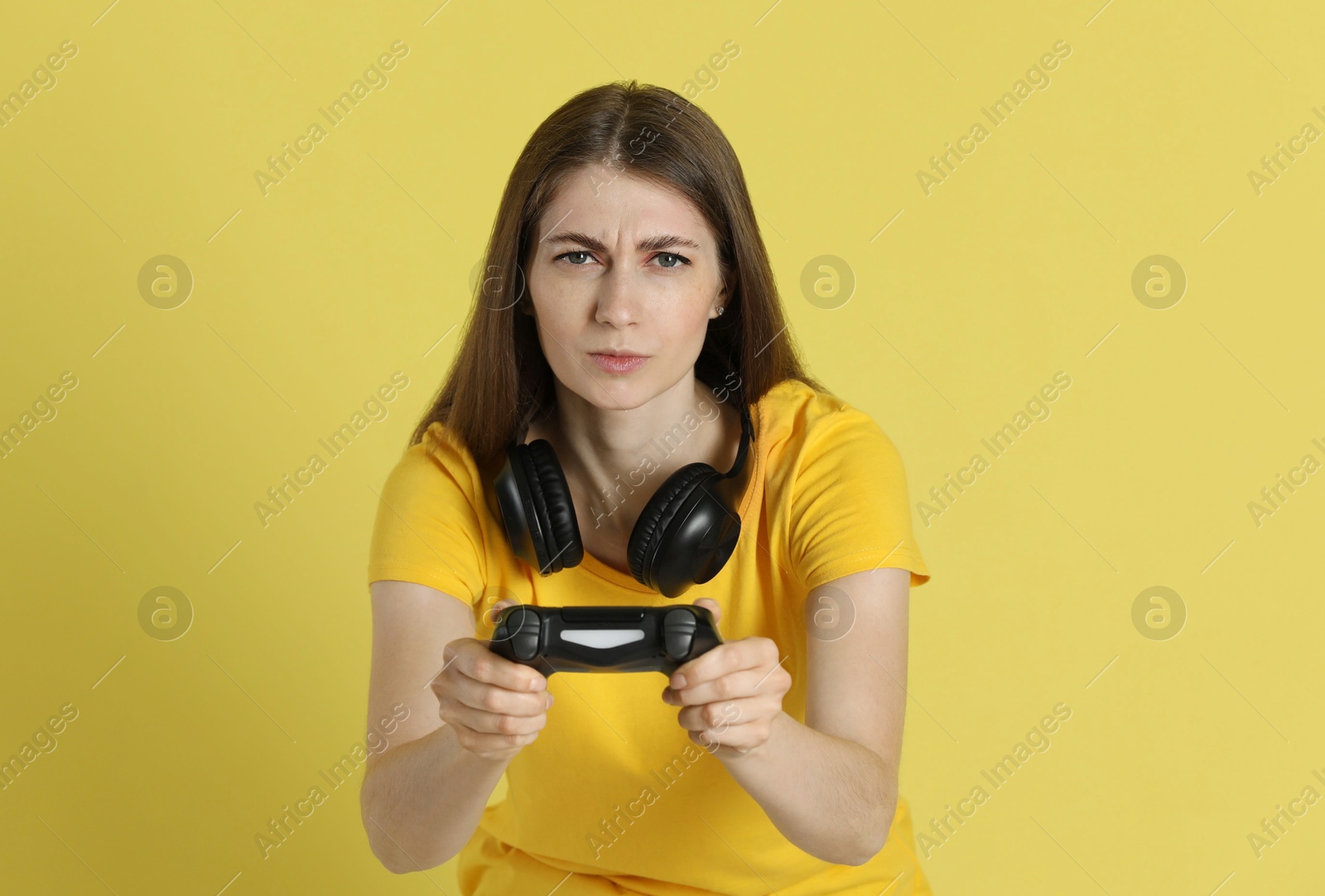 Photo of Woman playing video games with controller on yellow background