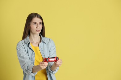 Woman playing video games with controller on yellow background, space for text