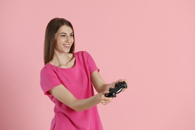 Photo of Happy woman playing video games with controller on pink background, space for text