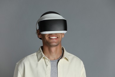 Photo of Smiling man using virtual reality headset on gray background