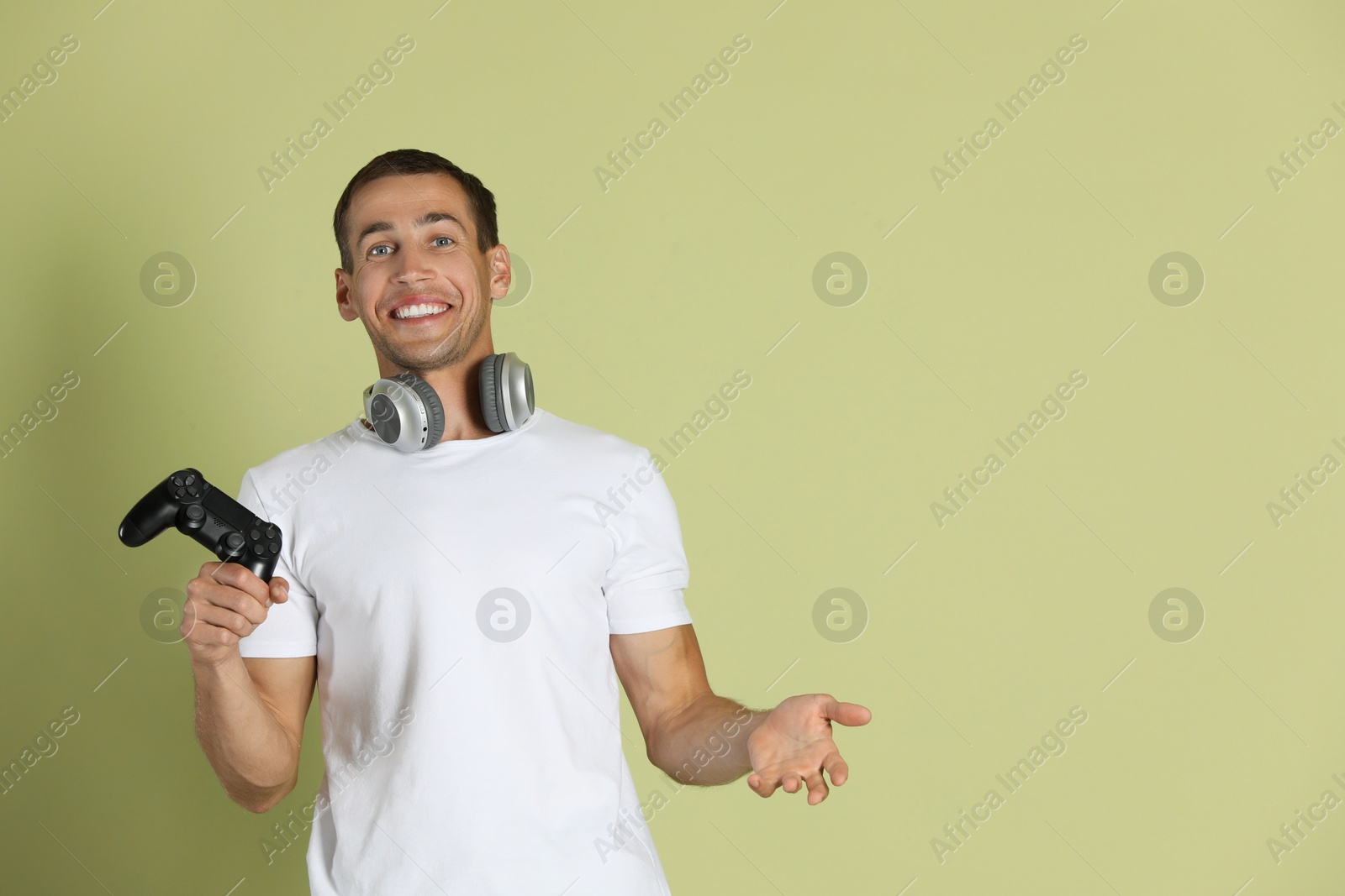 Photo of Happy man with controller on light green background, space for text