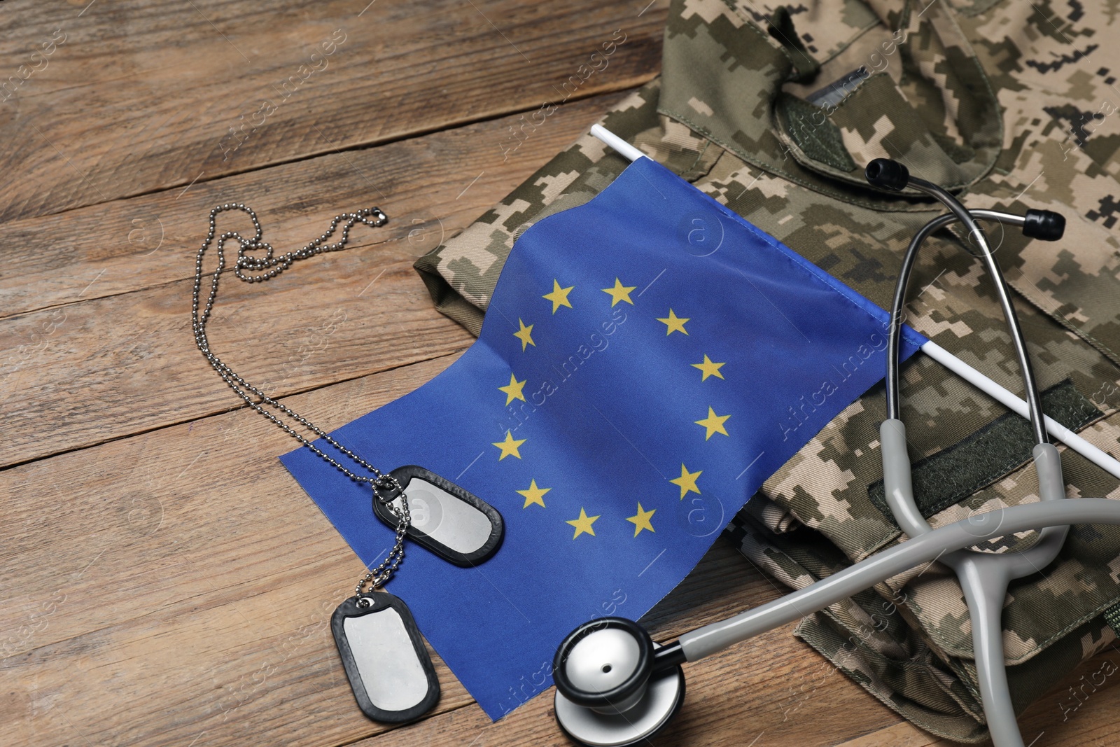 Photo of Stethoscope, flag of European Union, tags and military uniform on wooden table