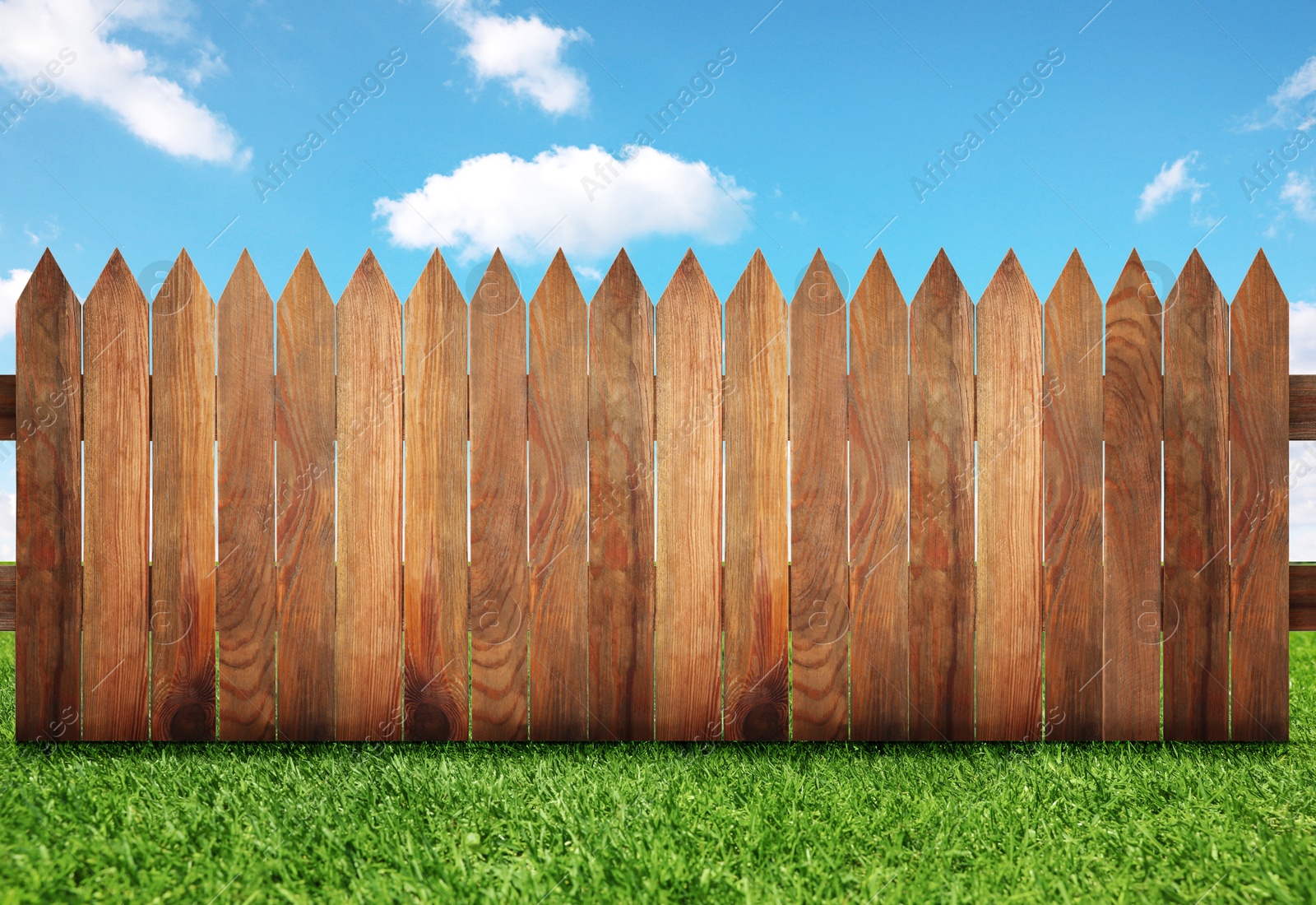 Image of Wooden fence and green grass under blue sky with clouds outdoors