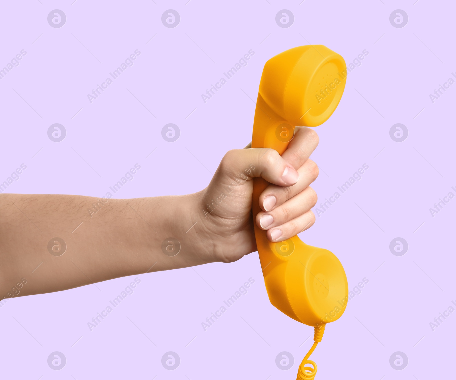 Image of Woman holding yellow telephone handset on light violet background, closeup