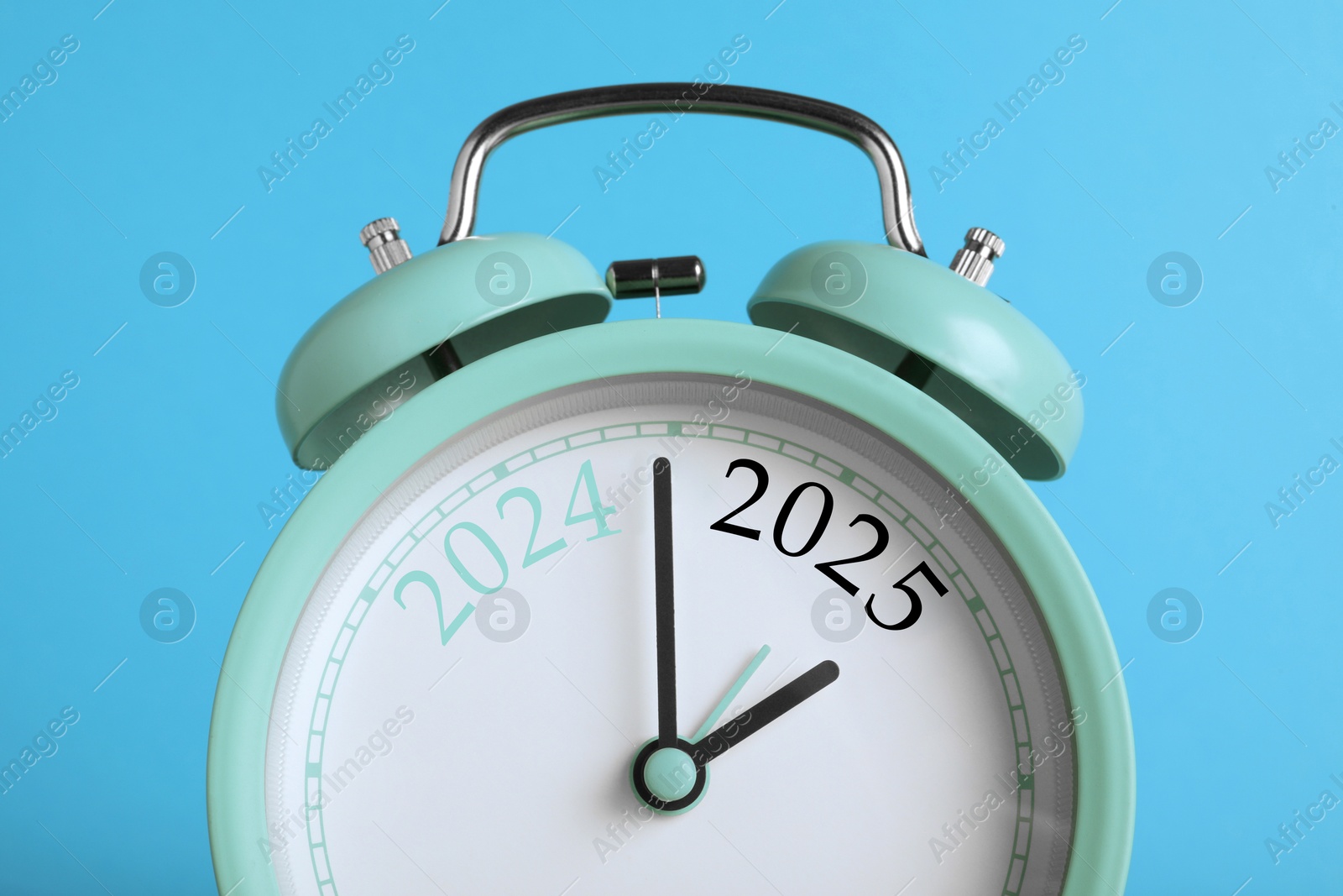 Image of Alarm clock with numbers 2024 and 2025 on light blue background, closeup. Beginning of new year