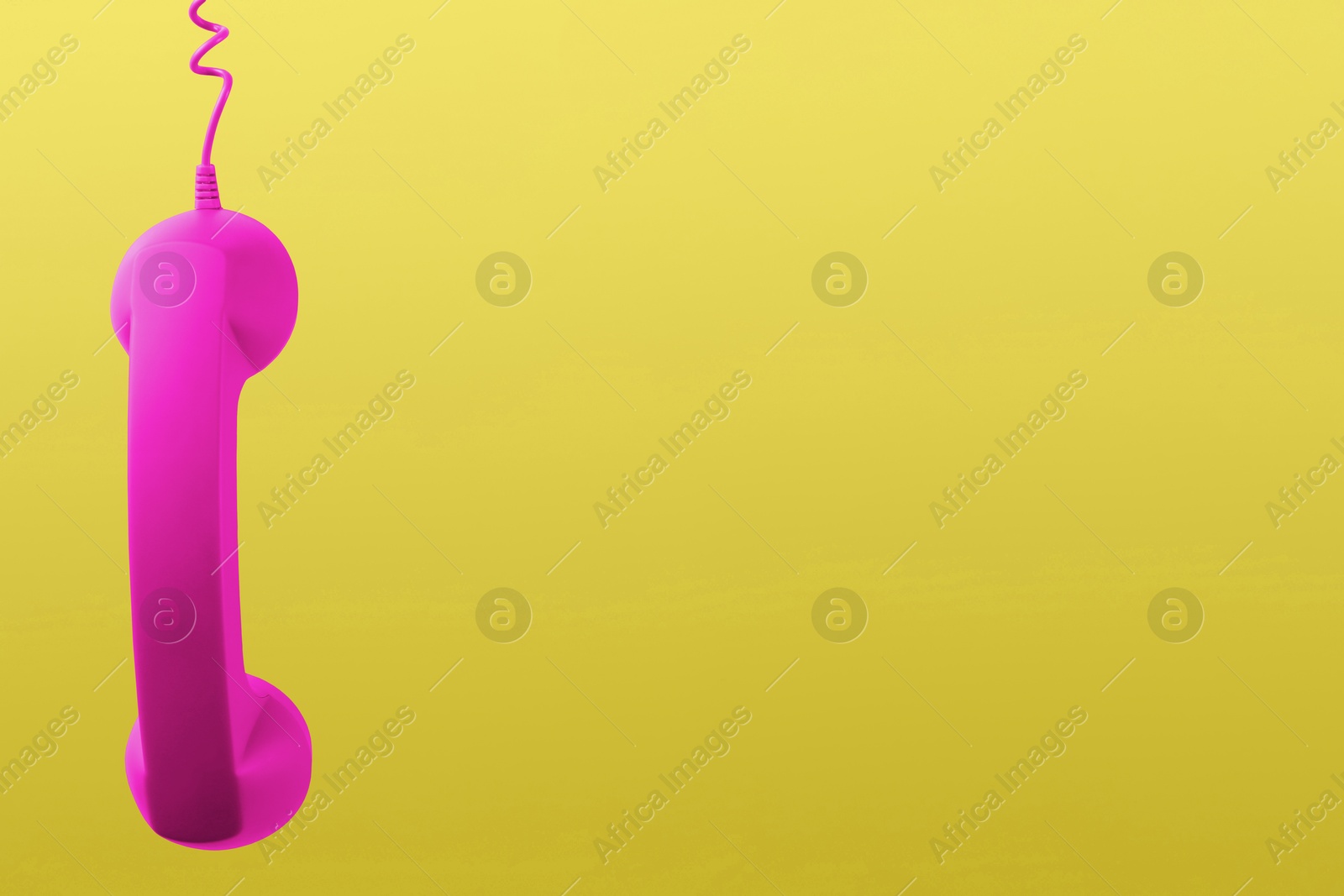 Image of Magenta telephone handset hanging on yellow background. Space for text
