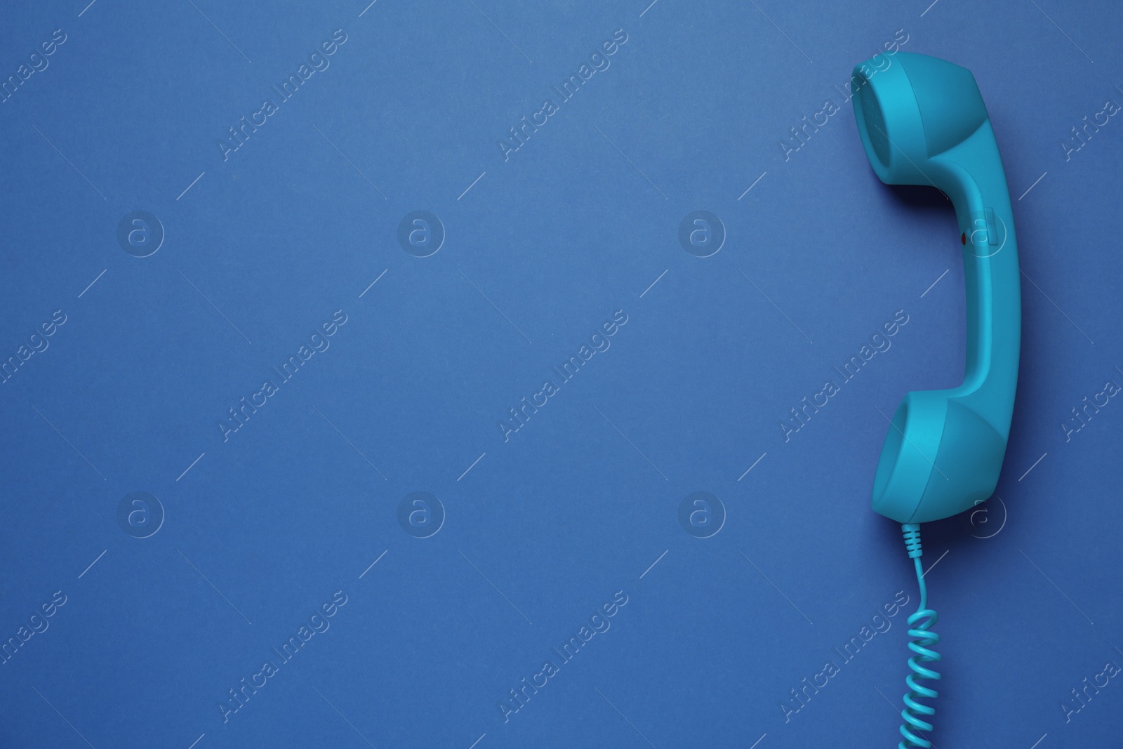 Image of Telephone handset on blue background, top view. Space for text