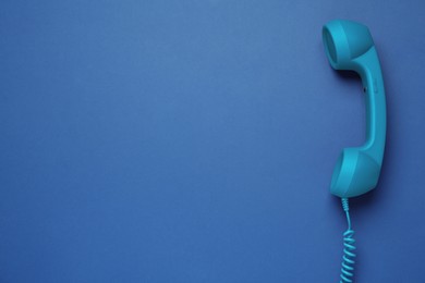 Telephone handset on blue background, top view. Space for text
