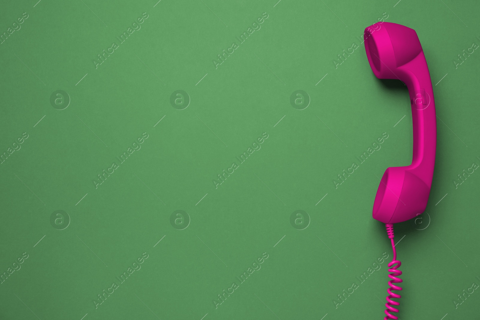 Image of Magenta telephone handset on green background, top view. Space for text