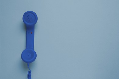 Blue telephone handset on grey background, top view. Space for text