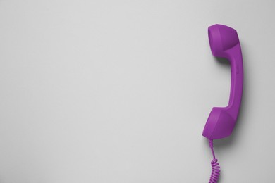 Purple telephone handset on light background, top view. Space for text