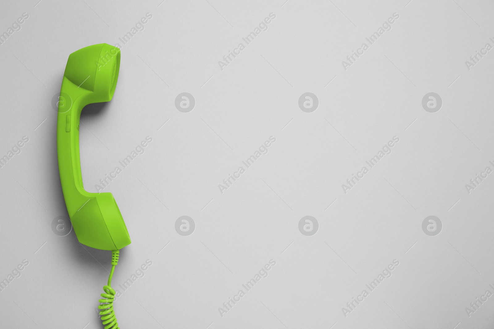 Image of Green telephone handset on light background, top view. Space for text