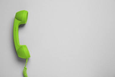 Image of Green telephone handset on light background, top view. Space for text