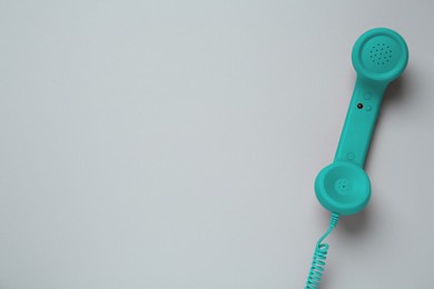 Turquoise telephone handset on light background, top view. Space for text