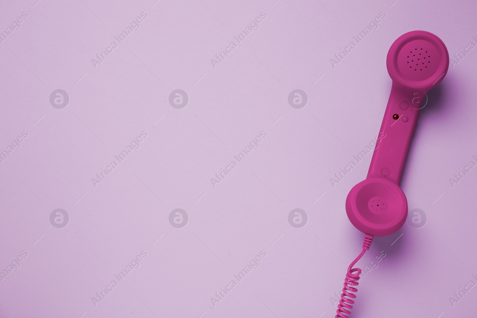 Image of Magenta telephone handset on pink background, top view. Space for text