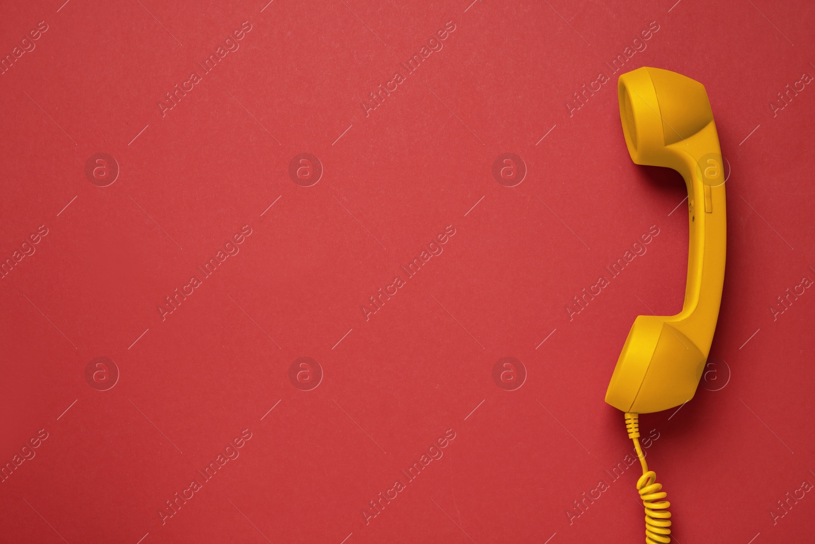 Image of Orange telephone handset on red background, top view. Space for text