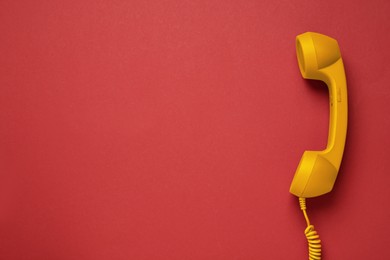 Image of Orange telephone handset on red background, top view. Space for text