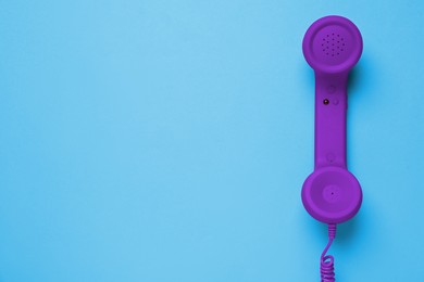 Image of Purple telephone handset on light blue background, top view. Space for text