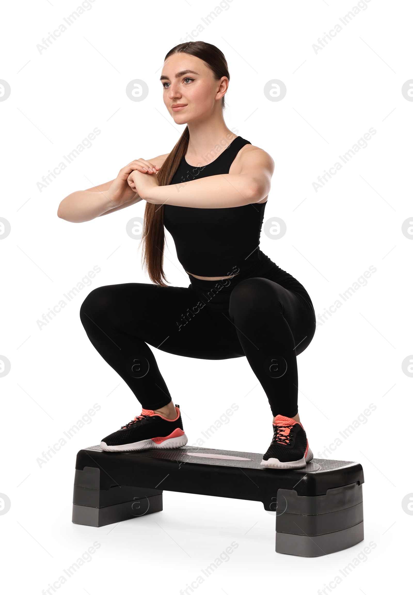 Photo of Young woman doing aerobic exercise with step platform on white background