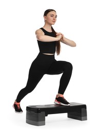 Young woman doing aerobic exercise with step platform on white background