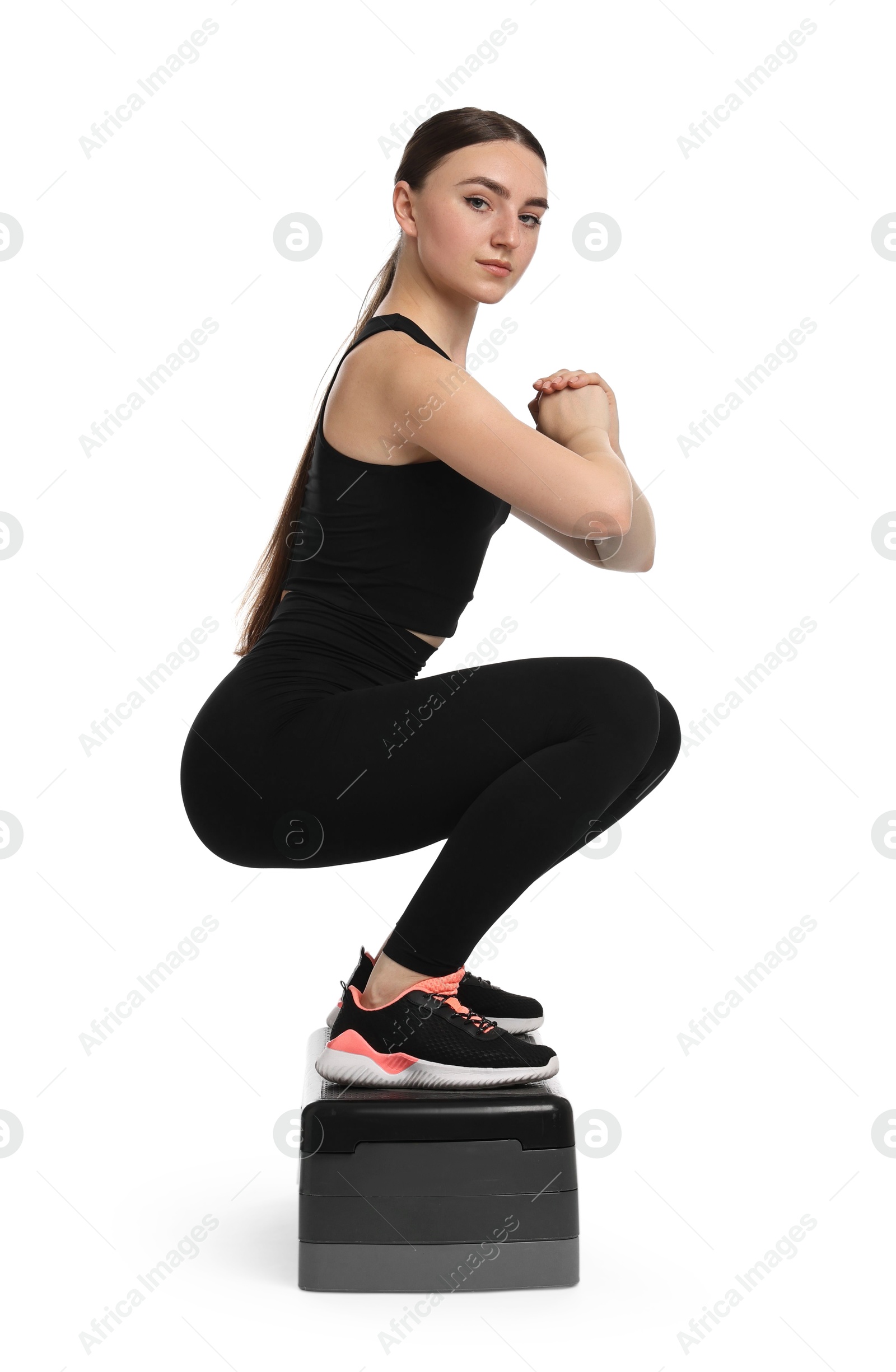 Photo of Young woman doing aerobic exercise with step platform on white background