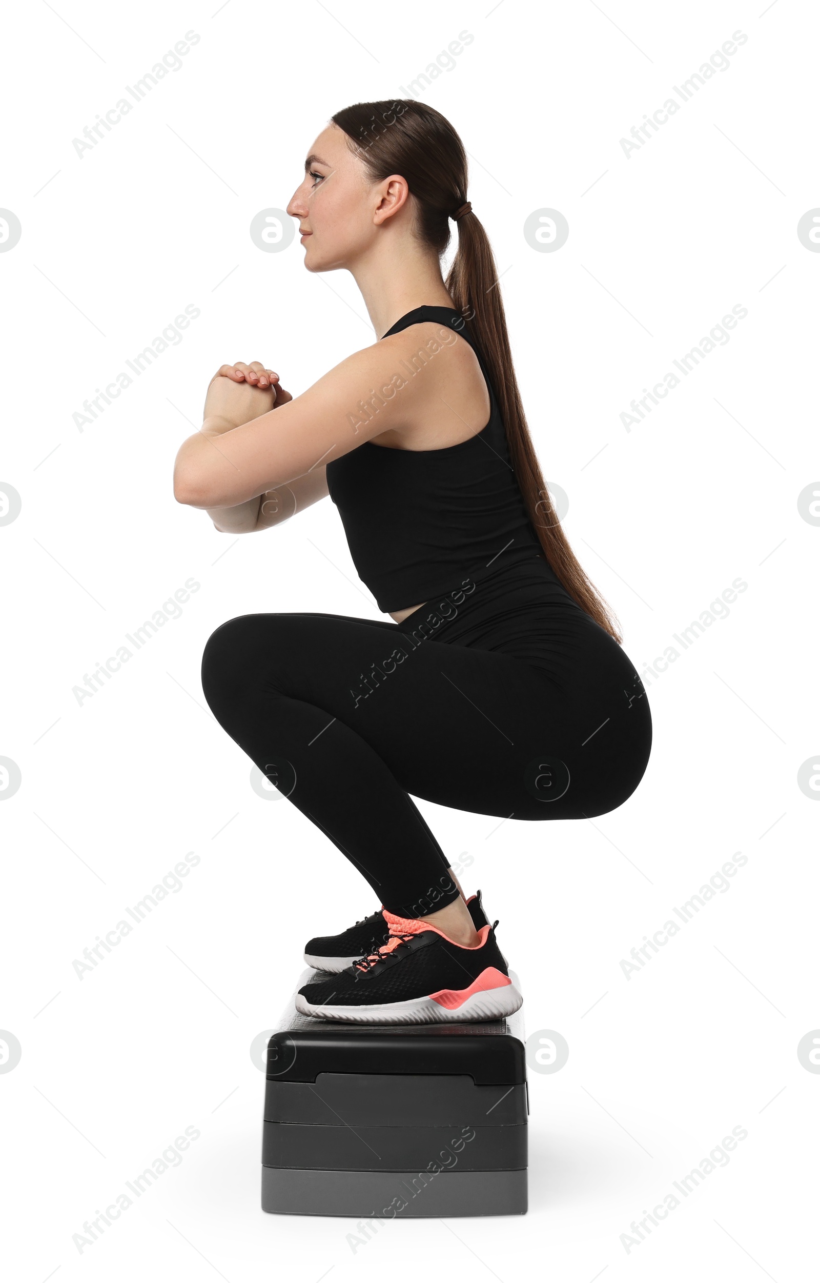 Photo of Young woman doing aerobic exercise with step platform on white background