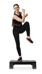 Young woman doing aerobic exercise with step platform on white background