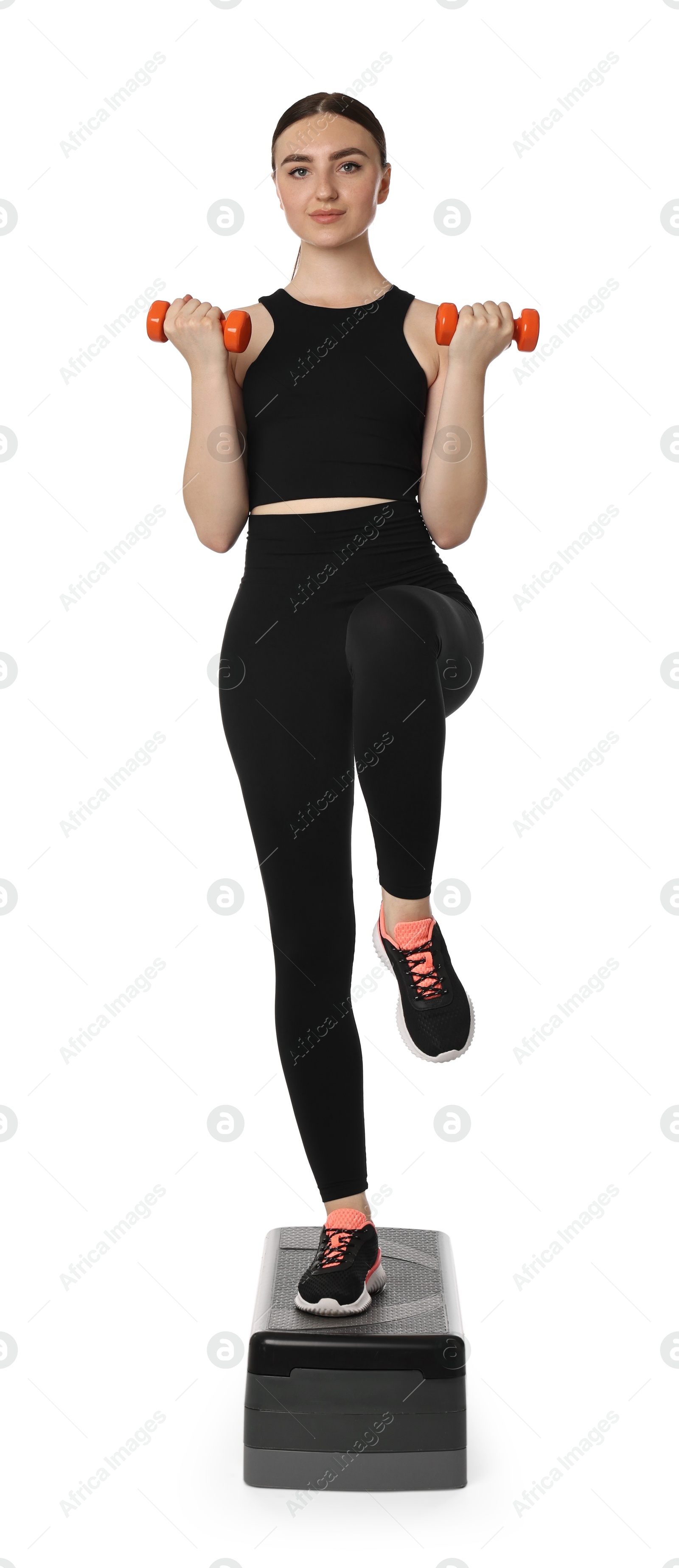 Photo of Young woman doing aerobic exercise with dumbbells and step platform on white background