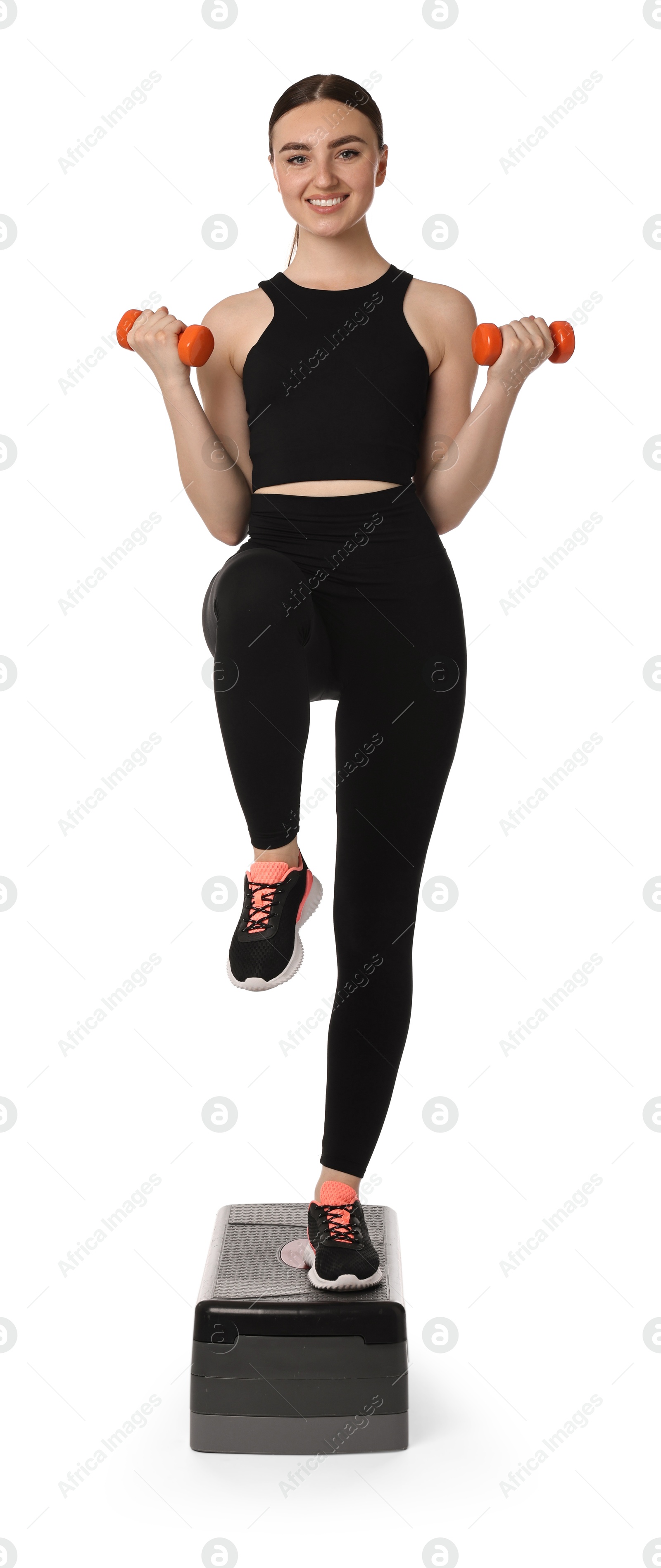 Photo of Young woman doing aerobic exercise with dumbbells and step platform on white background