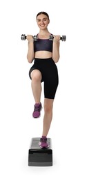 Young woman doing aerobic exercise with dumbbells and step platform on white background