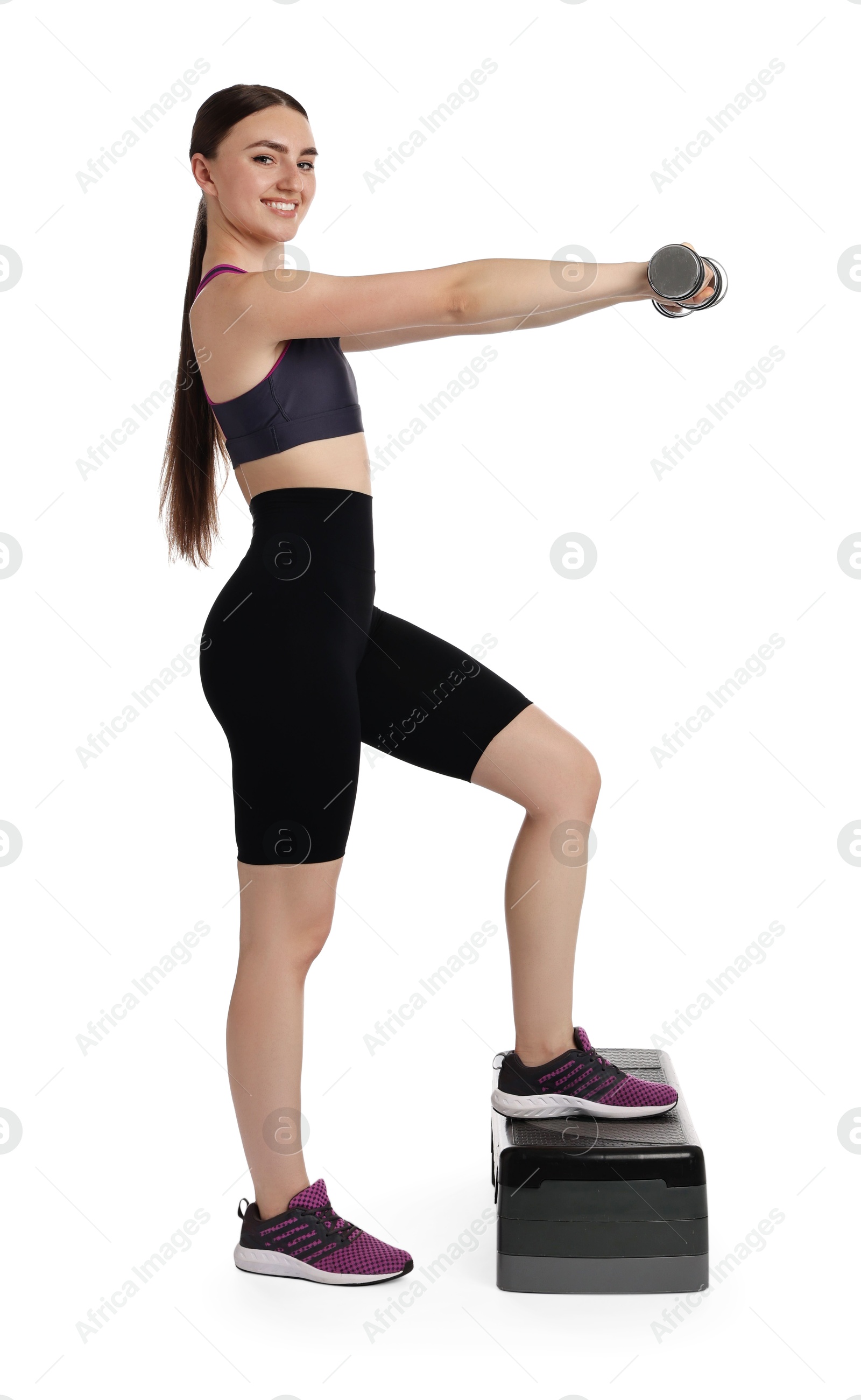 Photo of Young woman doing aerobic exercise with dumbbells and step platform on white background