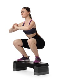 Photo of Young woman doing aerobic exercise with step platform on white background