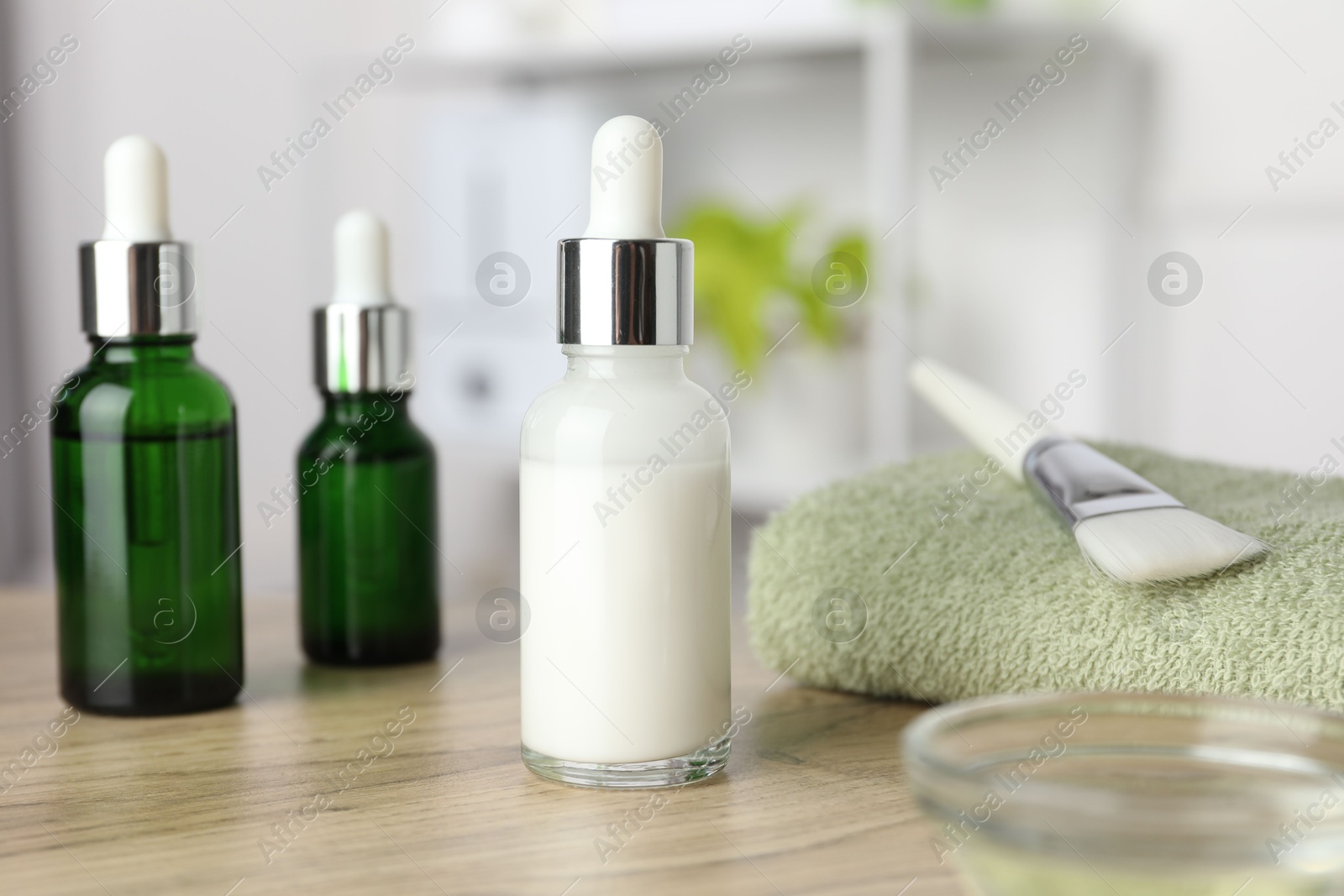 Photo of Peeling procedure. Bottles of chemical peel, bowl with liquid, towel and brush on wooden table indoors