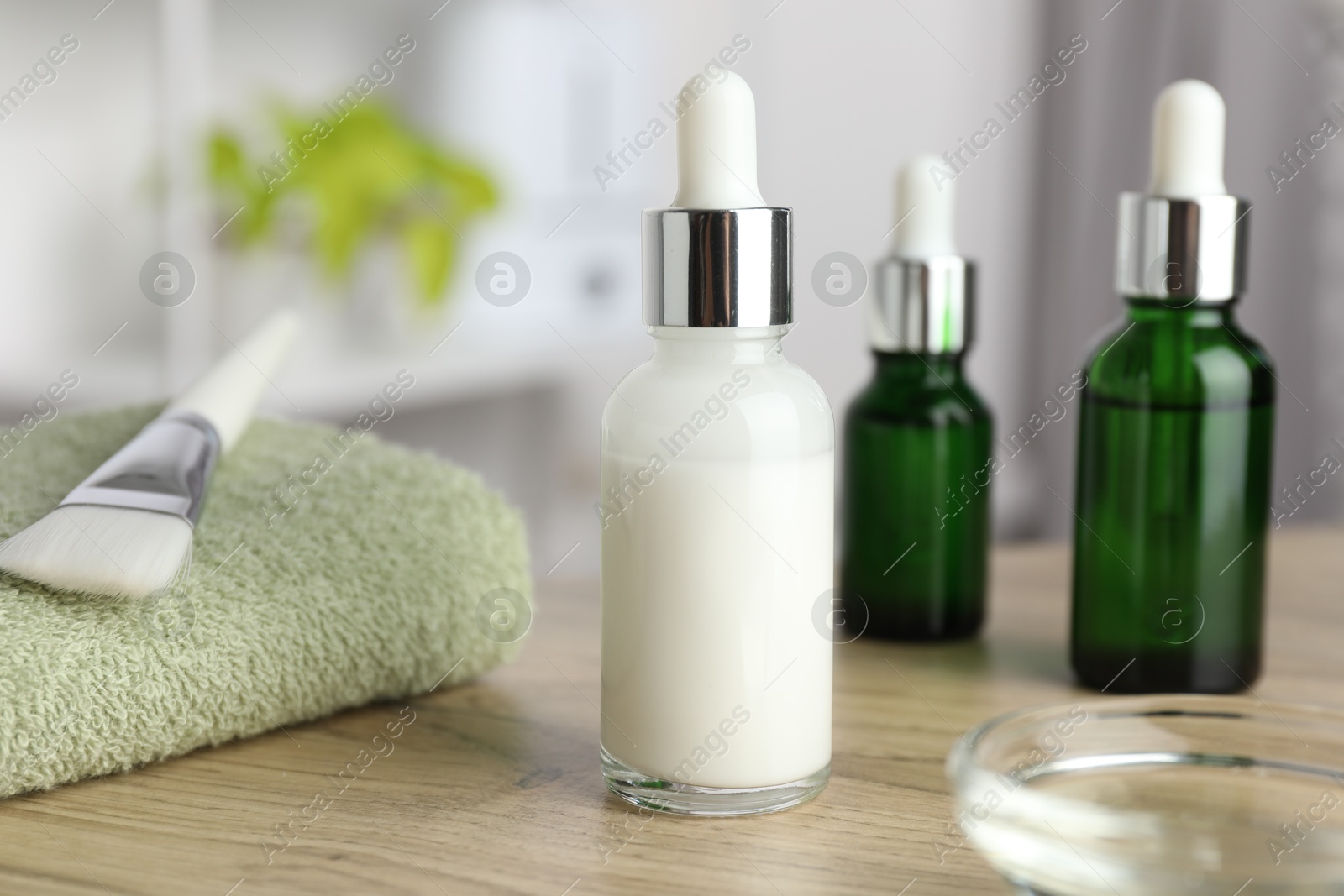 Photo of Peeling procedure. Bottles of chemical peel, towel and bowl with liquid on wooden table indoors