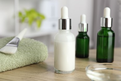 Photo of Peeling procedure. Bottles of chemical peel, towel and bowl with liquid on wooden table indoors