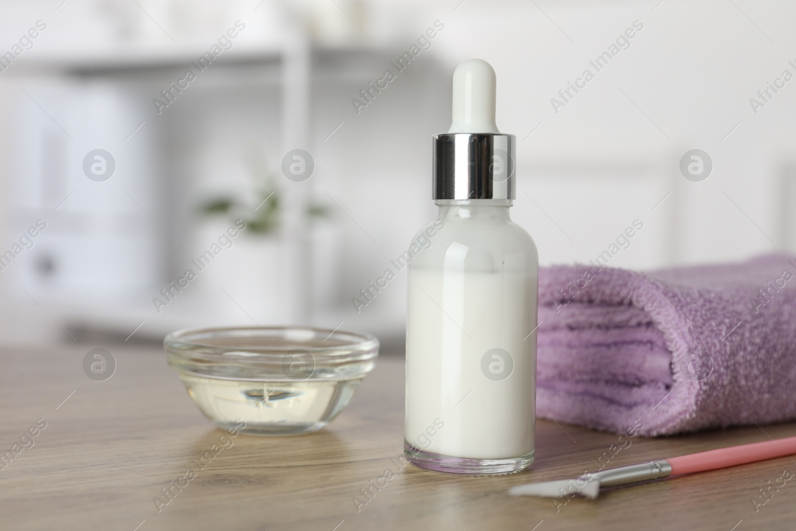 Photo of Peeling procedure. Bottle of chemical peel, bowl with liquid, towel and brush on wooden table indoors. Space for text