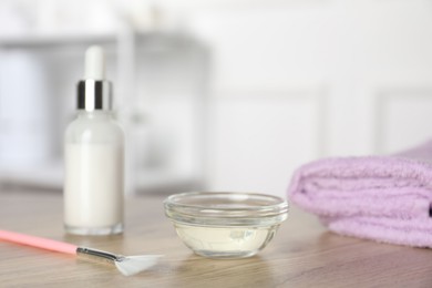 Photo of Peeling procedure. Bottle of chemical peel, bowl with liquid, towel and brush on wooden table indoors. Space for text